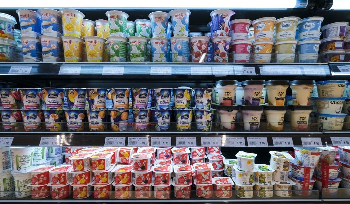 Various brands of yogurt on the shelf in a grocery store.