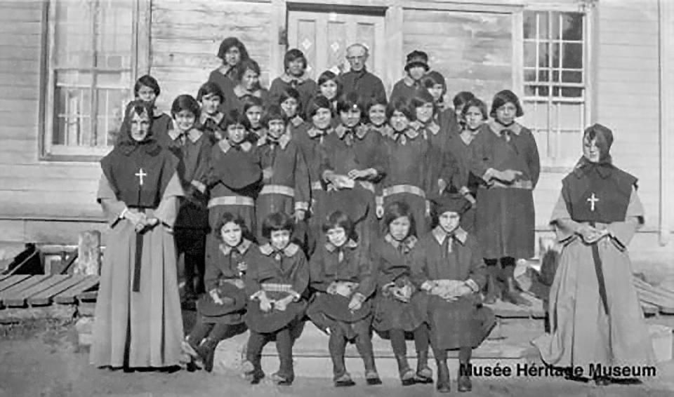 Grey nuns, Father J. Angin and school girls at Saddle Lake, Alta., c. 1922-1929. Saddle Lake Cree Nation is investigating possible burial sites near the site where Blue Quills residential school operated between the years 1898 and 1931. (Musée Héritage Museum - image credit)