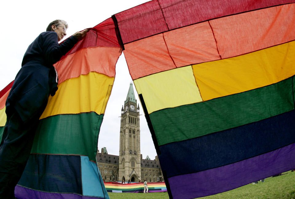 Silvie Small holds up a section of a 500 foot rainbow flag around Parliament Hill in support of same-sex marriage in Ottawa, June 19, 2005. REUTERS/Jim Young