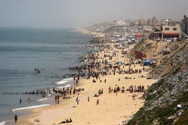 فلسطينيون يهربون إلى شاطئ دير البلح وسط قطاع غزة في يوم شديد الحرارة في 24 أبريل/نيسان 2024.